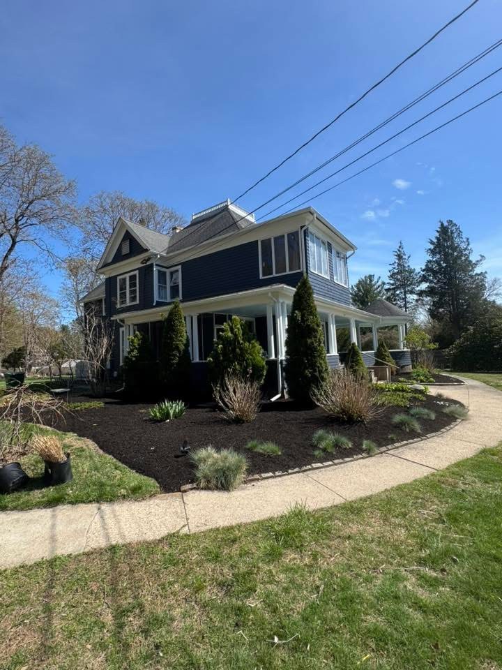 Garden beds around a blue house after mulching